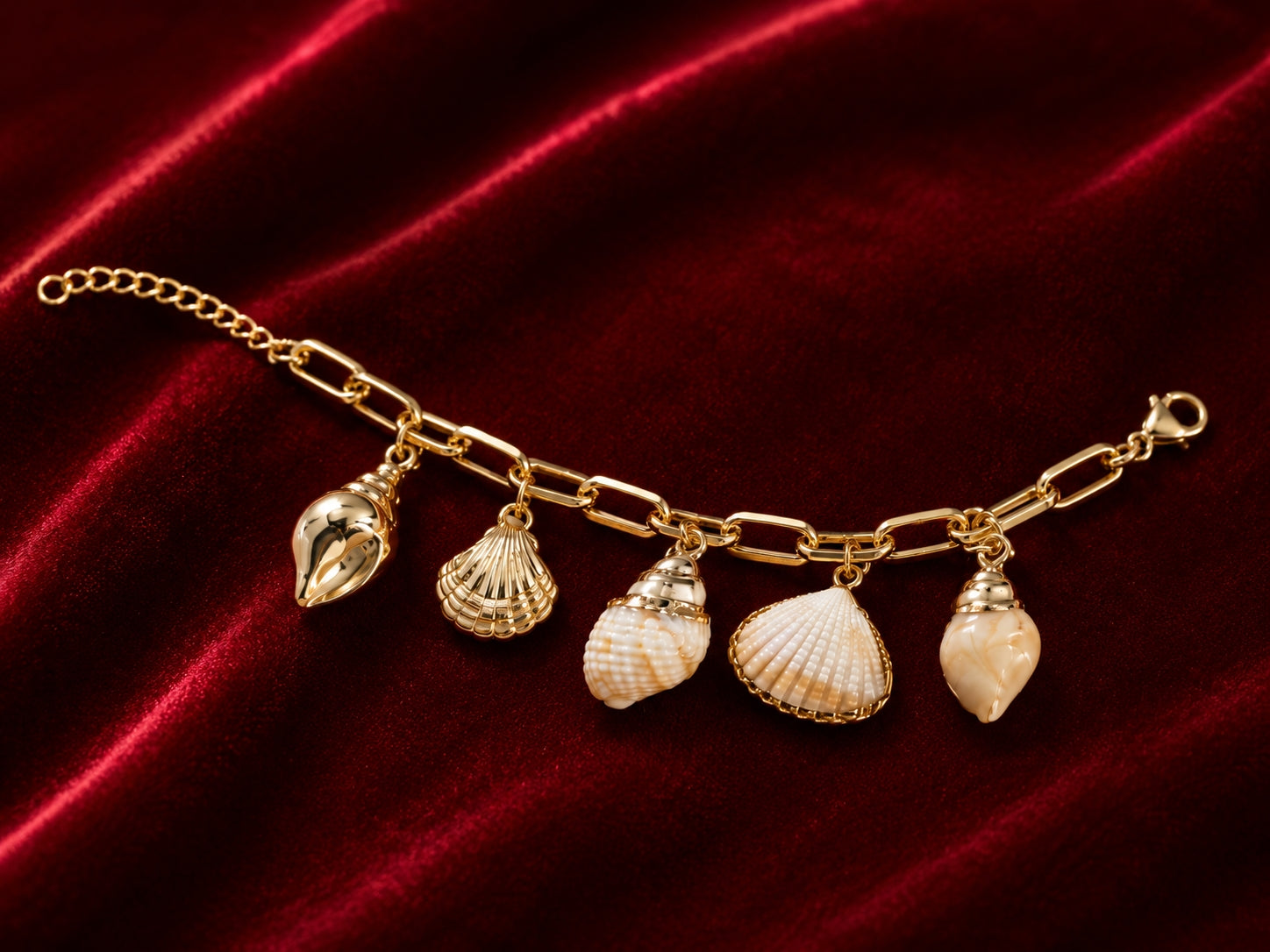 Beach-inspired gold shell charm bracelet flat lay on beige satin
