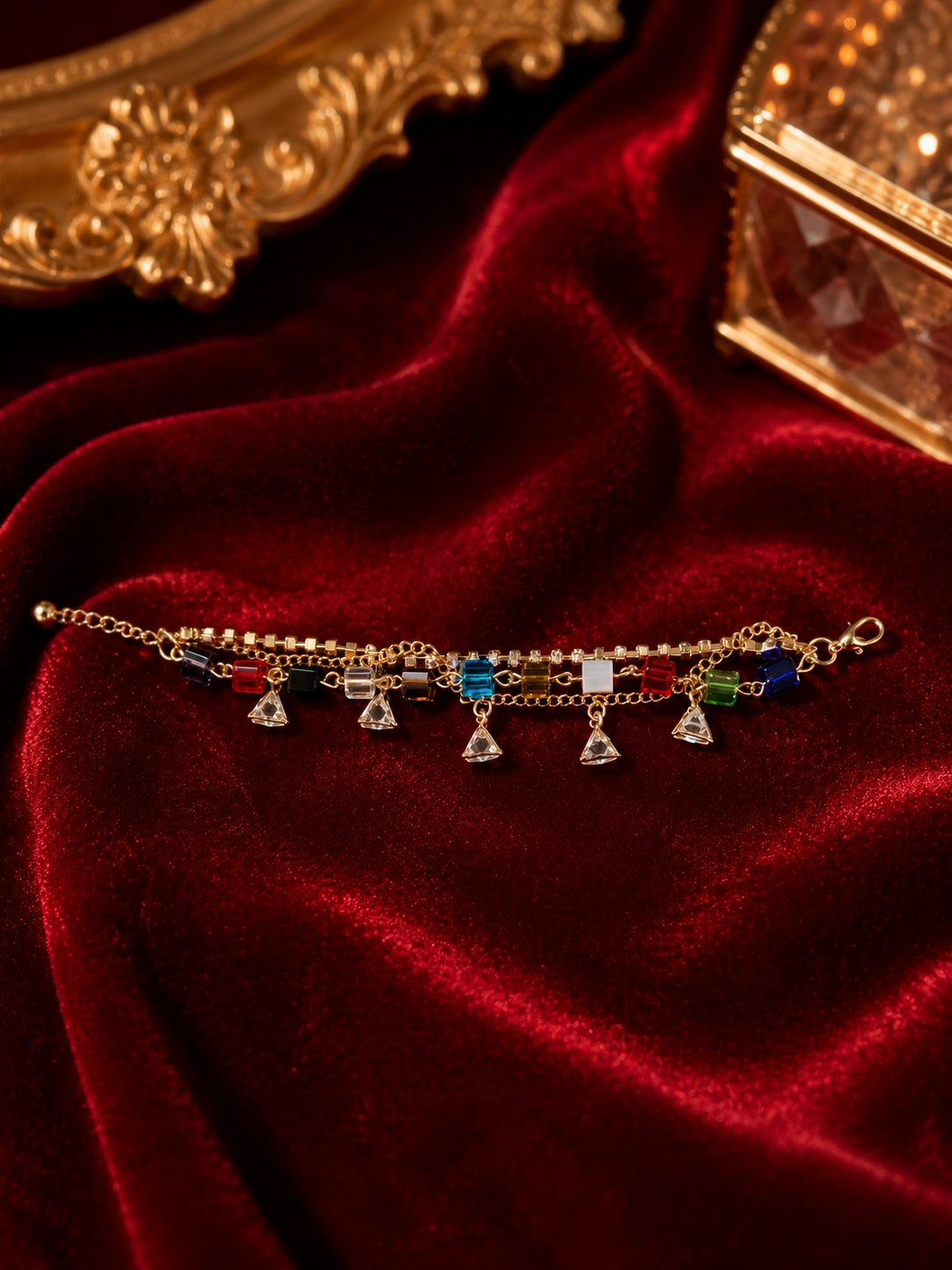 Gold-toned multicolour crystal cube charm bracelet flat lay on red velvet background