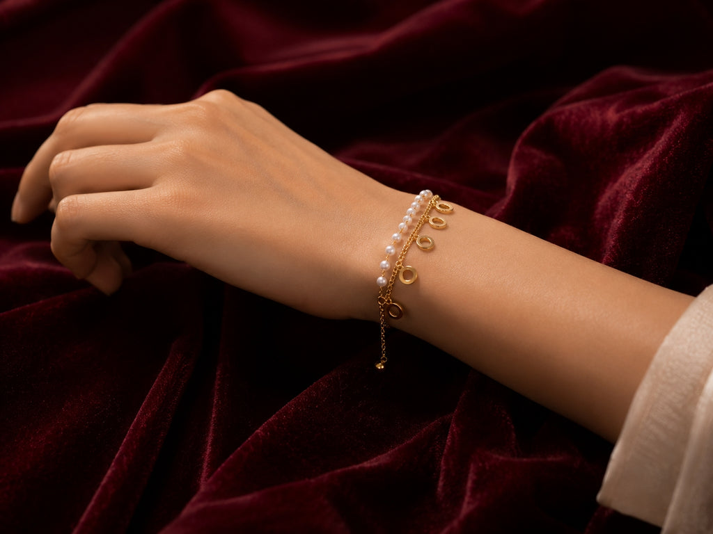 Model wearing gold circle charm bracelet on wrist against burgundy velvet