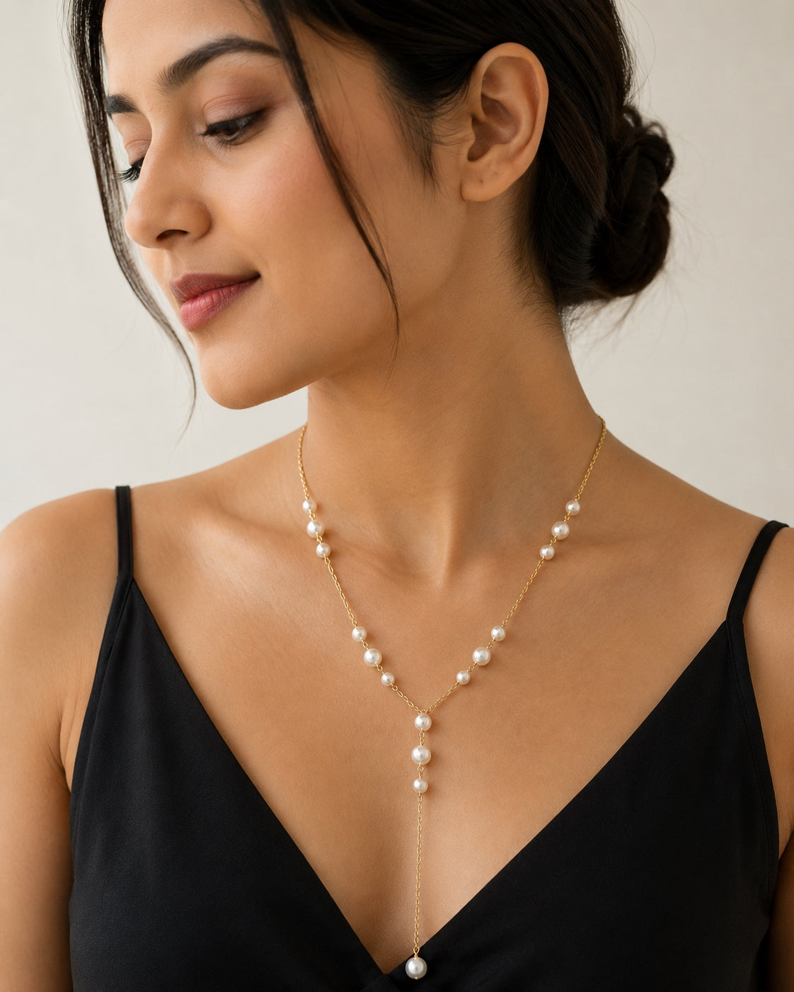 Gold-toned Y pearl necklace model wearing on black top with updo hairstyle