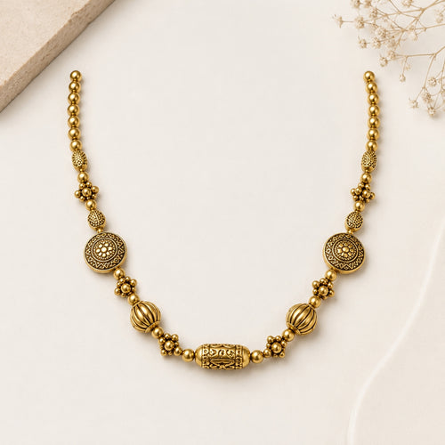 Antique gold beaded necklace on cream mannequin bust