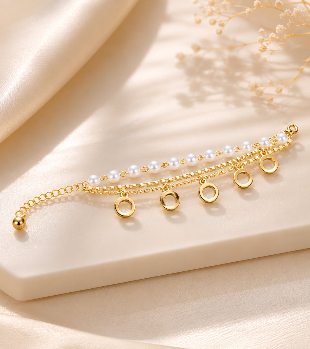 Pearl beaded bracelet with gold circle charms on white marble surface with flowers