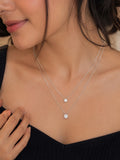 Model wearing silver double layer CZ bezel pendant necklace on black top