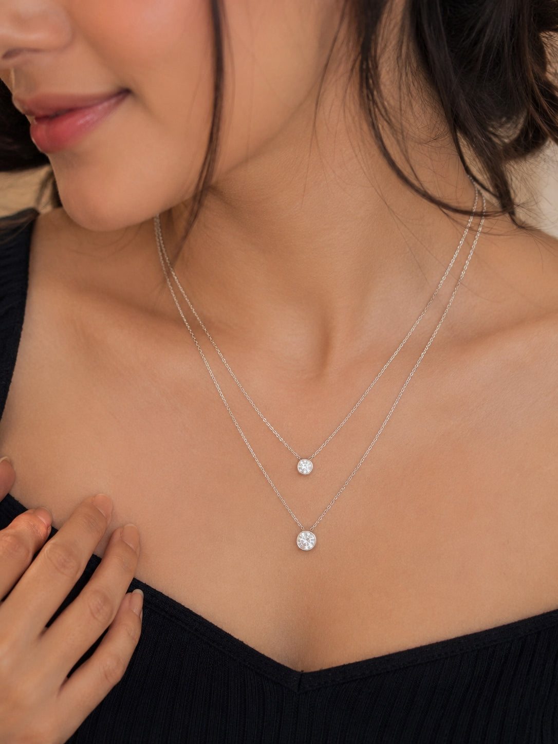 Model wearing silver double layer CZ bezel pendant necklace on black top