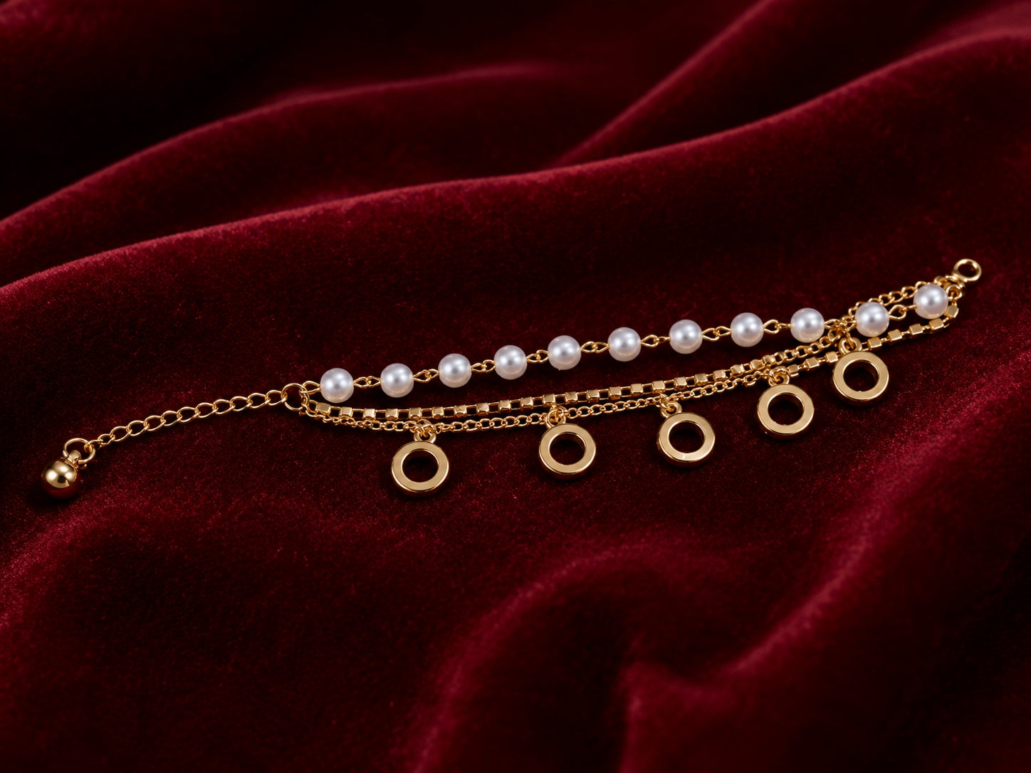 Gold layered pearl circle charm bracelet flat lay on burgundy velvet
