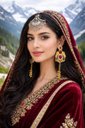 Woman wearing Kashmiri gold jhumka earrings with red stone and bridal outfit