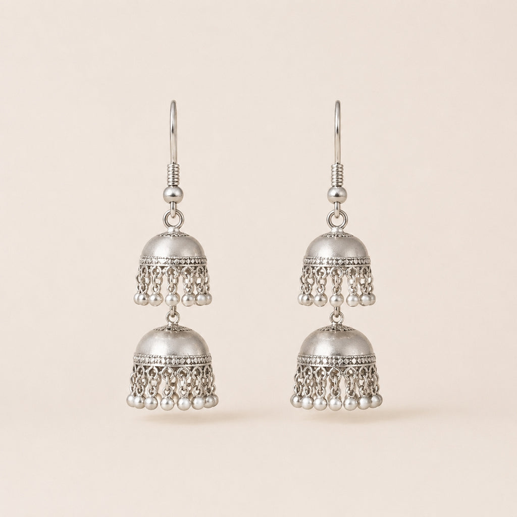 Oxidised silver double jhumka earrings with pearl drops on cream background