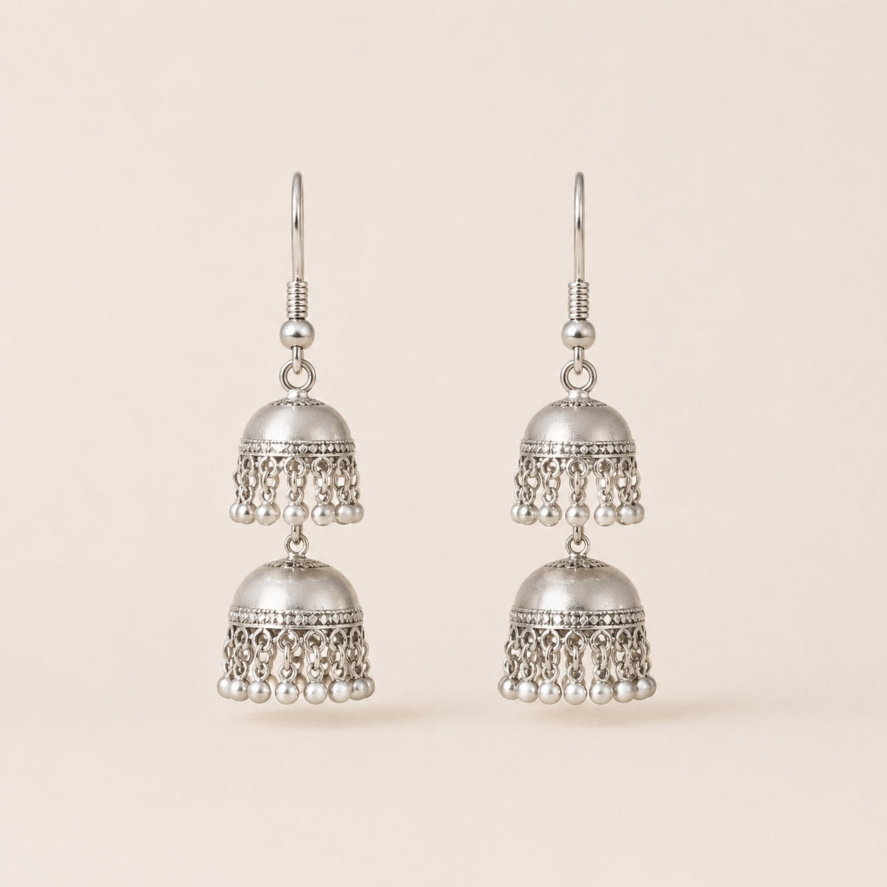 Oxidised silver double jhumka earrings with pearl drops on cream background